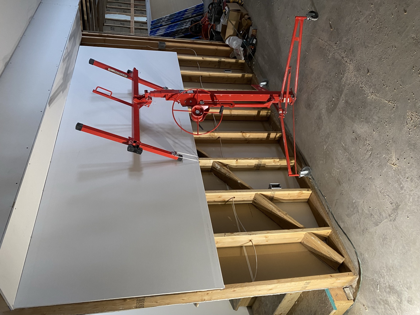 Drywall lift holding a sheet in place on a framed interior wall mid-renovation